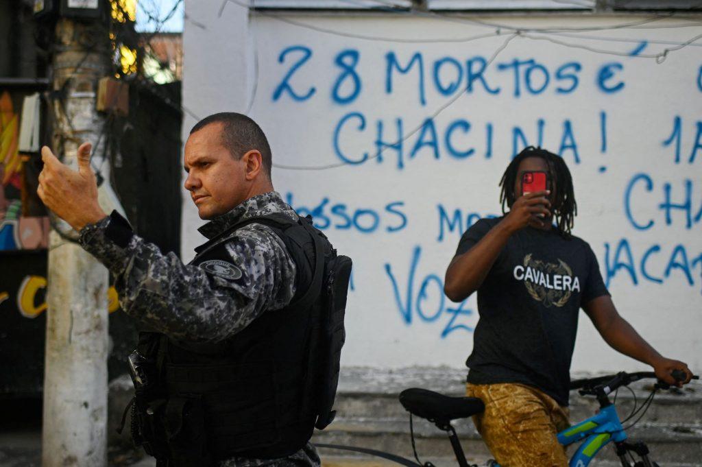 Homem filma policial na comunidade de Jacarezinho e no muro se lê “28 mortos é chacina”